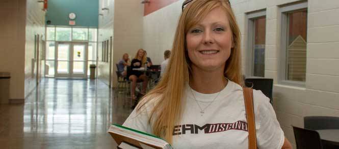 Business programs - female student smiling in front other students in background